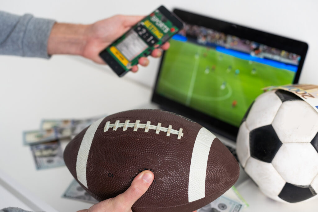 un homme tient un ballon de rugby et son téléphone