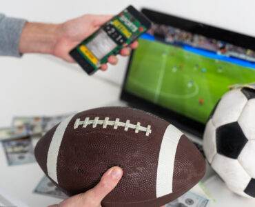 un homme tient un ballon de rugby et son téléphone