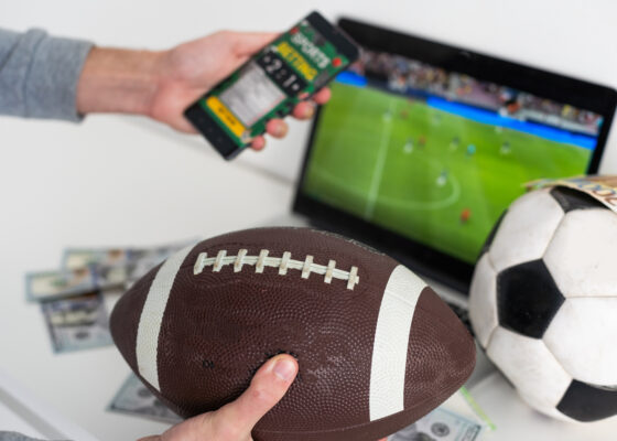 un homme tient un ballon de rugby et son téléphone