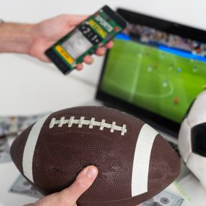 un homme tient un ballon de rugby et son téléphone